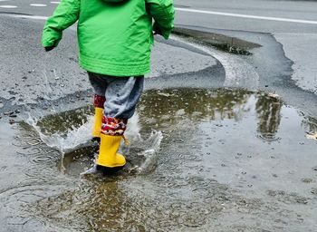 Reflection of man in puddle on street during rainy season