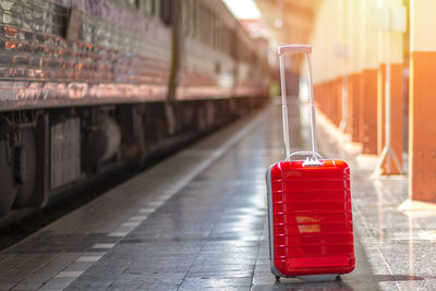 Red wheeled luggage at railroad station platform