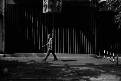 Side view of woman walking on footpath against building