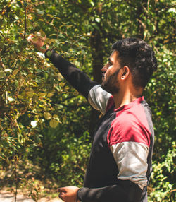 Side view of young man against forest