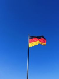 Low angle view of flag against clear blue sky