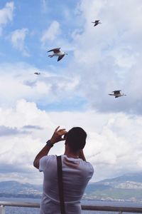 Person flying kite against cloudy sky