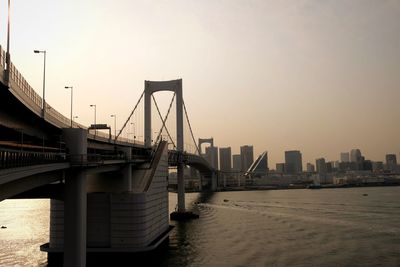 Bridge over river in city against sky