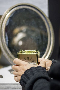 Close-up of person holding clock on table 