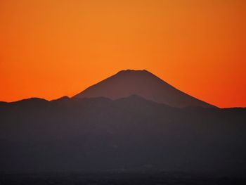 Scenic view of silhouette mountains against orange sky