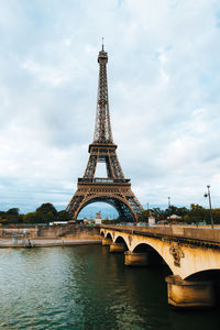 Arch bridge over river against cloudy sky