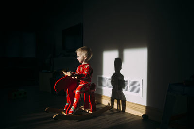 Baby boy looking away while sitting on rocking horse at home