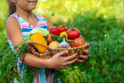Midsection of girl holding vegetables in hand