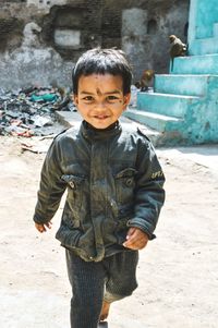 Portrait of smiling boy running on footpath