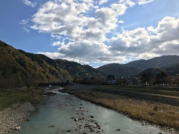 Scenic view of river by mountains against sky