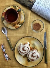 High angle view of cinnamon buns with tea on bed