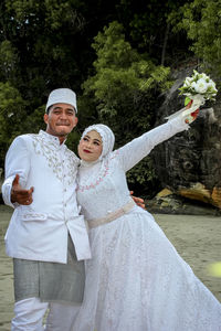 Portrait of a smiling couple standing against trees