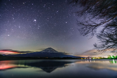 Scenic view of lake and mountains against sky at night