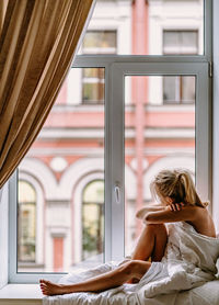 Woman sitting by window in bedroom