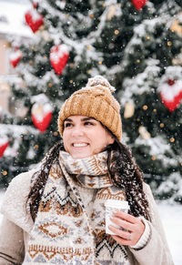 Portrait of a young woman drinking coffee from a paper coffee to go cup. winter, christmas, snowing.