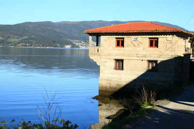 House by lake against sky