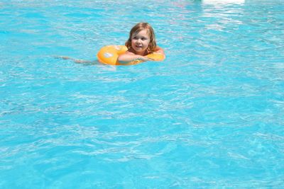 Smiling girl swimming in pool during sunny day