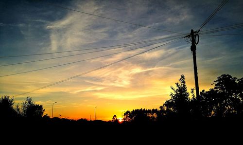 Low angle view of silhouette trees against cloudy sky