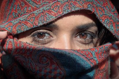 Close-up portrait of woman covering face with scarf