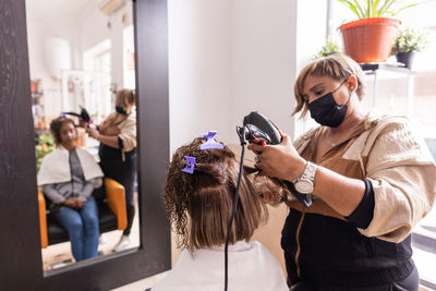 Hairdresser styling hair of customer at saloon