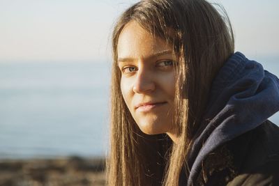 Close-up portrait of smiling young woman against sea and sky