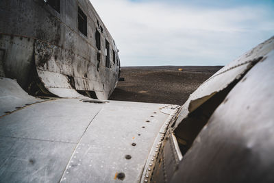 Abandoned airplane on sea shore against sky