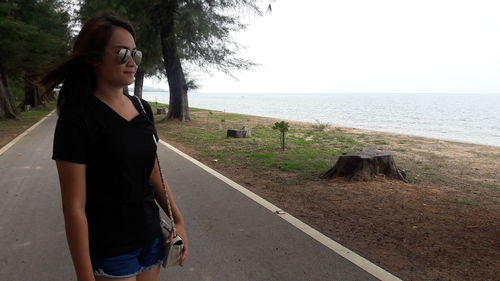 Beautiful woman standing by sea against sky