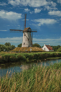 Canal with old windmill and bushes near damme. a charming country village in belgium.