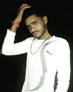 Portrait of young man standing against black background