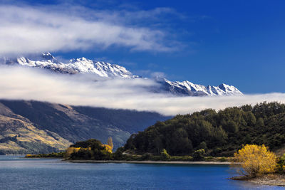 Scenic view of lake by mountains against sky