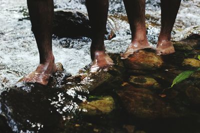 Low section of man standing on wet shore