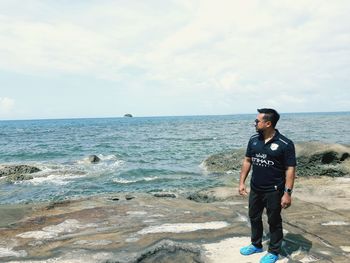 Full length of man standing at beach against sky