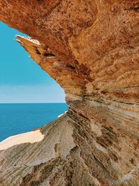 Rock formation on beach against sky