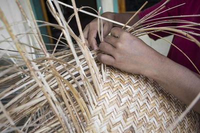 Midsection of man making wicker basket