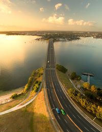 High angle view of illuminated city by sea at sunset