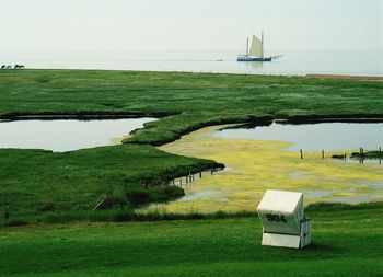 Scenic view of agricultural field by sea against sky