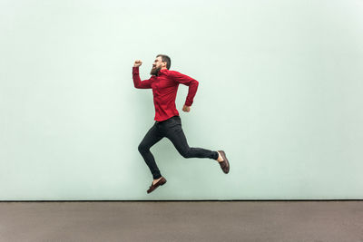 Full length of young man jumping against white background