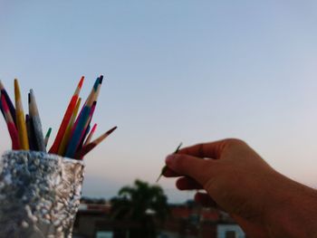 Close-up of hand holding multi colored against clear sky