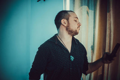 Young man looking away against wall