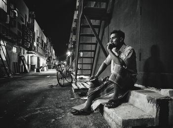 Thoughtful man sitting on steps in city at night