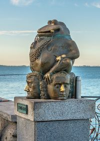 Statue by sea against sky