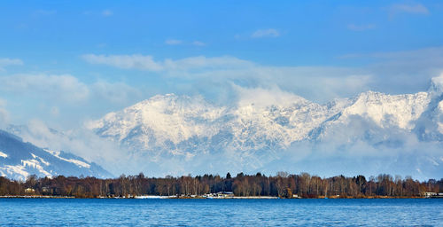 Scenic view of lake by snowcapped mountains against sky