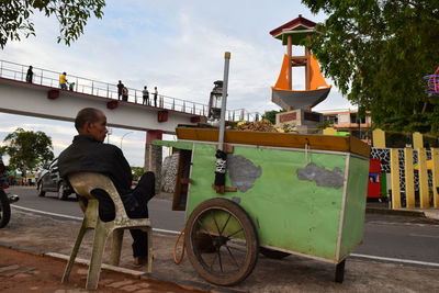 Rear view of man sitting on seat against sky