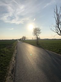 Road amidst field against sky