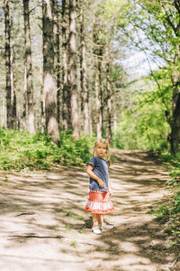 Girl standing against trees in forest