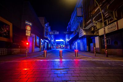 Illuminated street lights on sidewalk by buildings at night