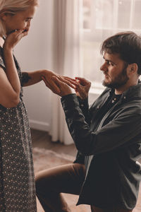 Smiling man proposing girlfriend at home