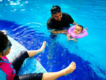 Father swimming with children in pool
