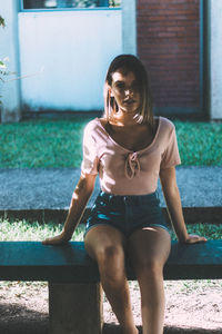 Portrait of teenage girl sitting on bench at park