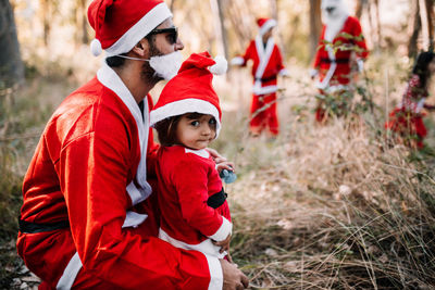 Father and daughter wearing santa costume in forest